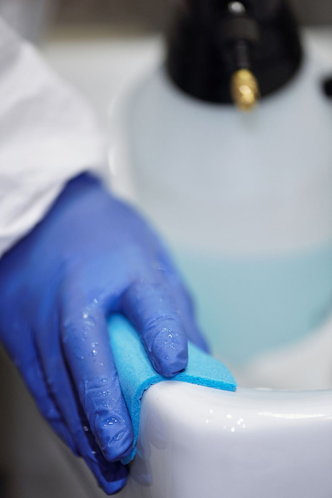 Gloved hands cleaning a sink