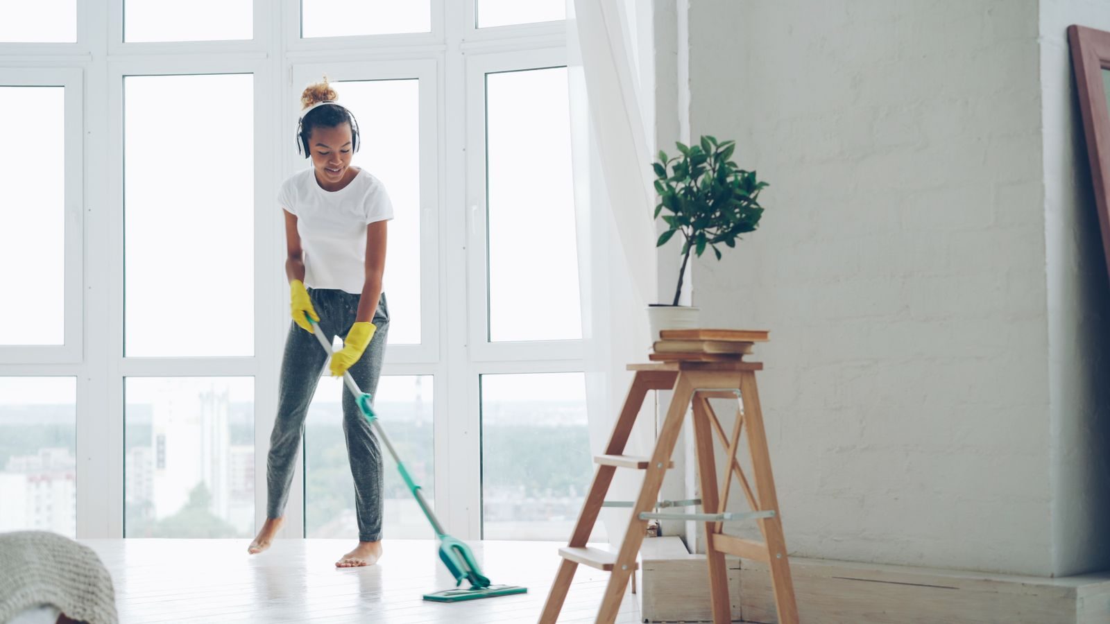 Cleaner mopping the floor of a bright, sunny room