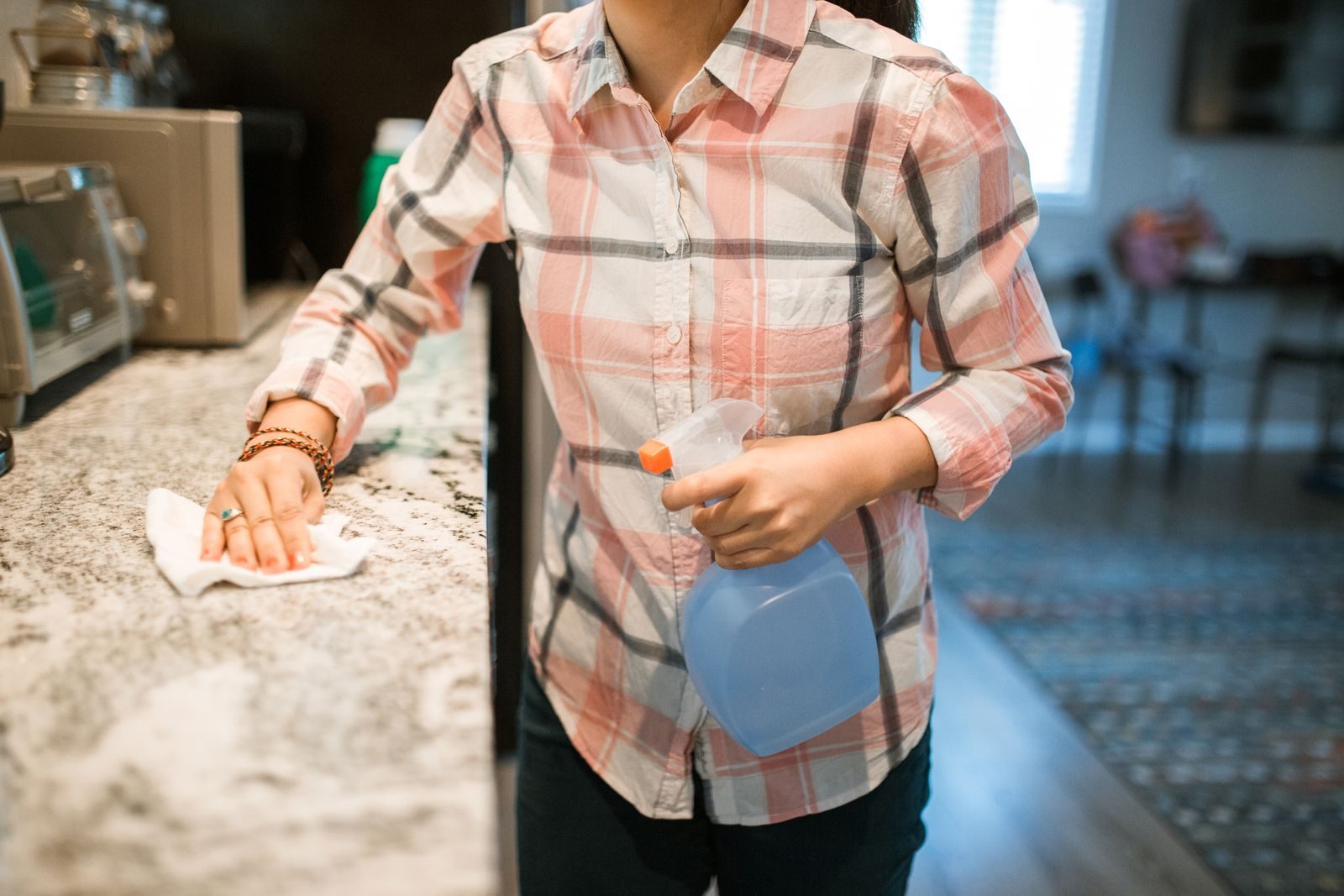 Cleaner wiping a kitchen counter with spray and cloth